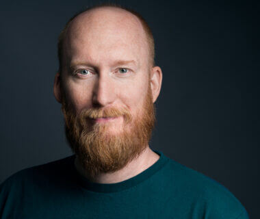Smiling photo of Flynn O'Connor, a white male with a ginger colored beard