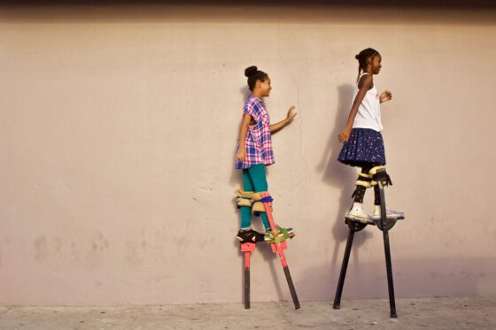 Girls on stilts getting to be taller than they thought